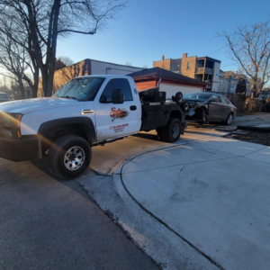 A tow truck from Soto Towing Inc. with a damaged grey sedan attached for towing in Chicago, IL.