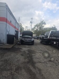 A tow truck with tires in the lot of Motor City Auto Care in Dayton, OH, indicating towing services.