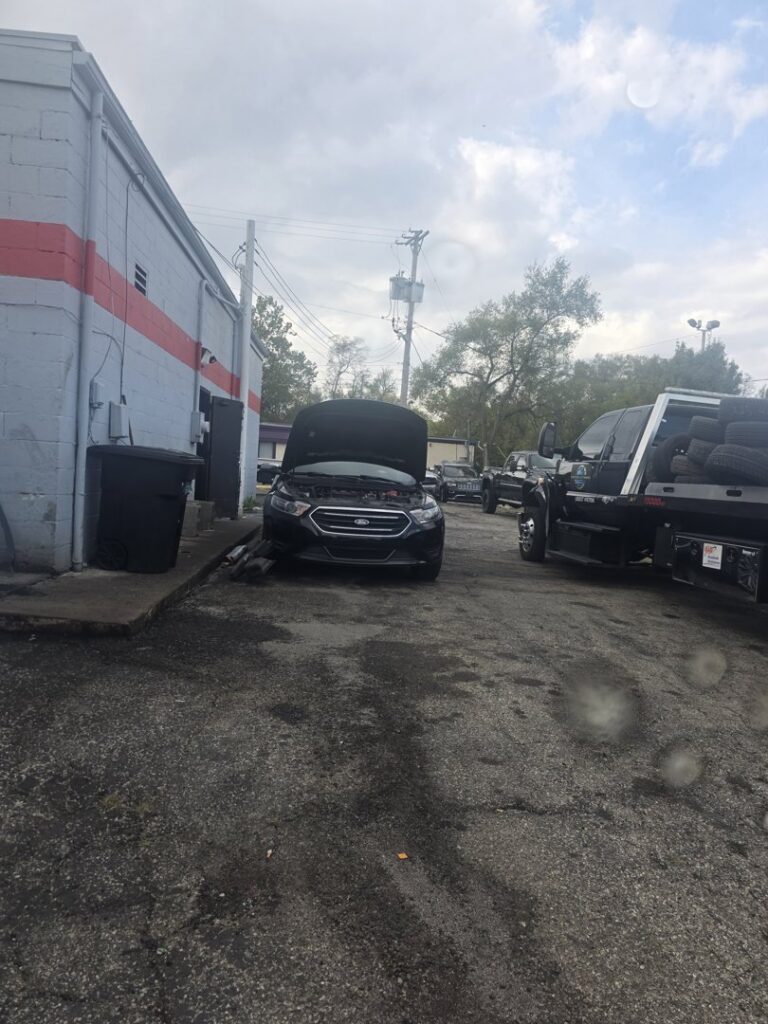A tow truck with tires in the lot of Motor City Auto Care in Dayton, OH, indicating towing services.