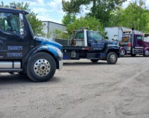 Two tow trucks, including a flatbed and a wrecker, parked in the lot at Harry's Body Shop & Towing in Jacksonville, FL