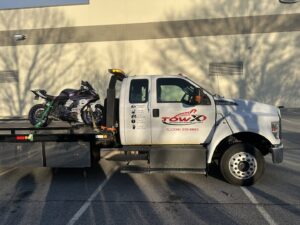 A Tow X flatbed tow truck transporting a purple motorcycle in Greensboro, NC.