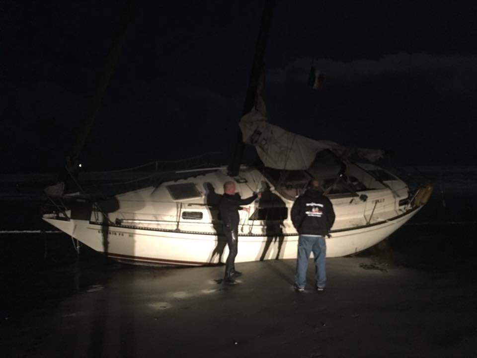TowBoatUS San Diego crew recovering a beached sailboat from the shore at night in San Diego, CA.