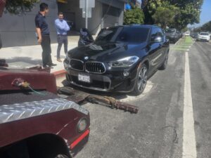 Orellanas Towing & Junk Car tow truck actively towing a black BMW SUV in Los Angeles, CA.