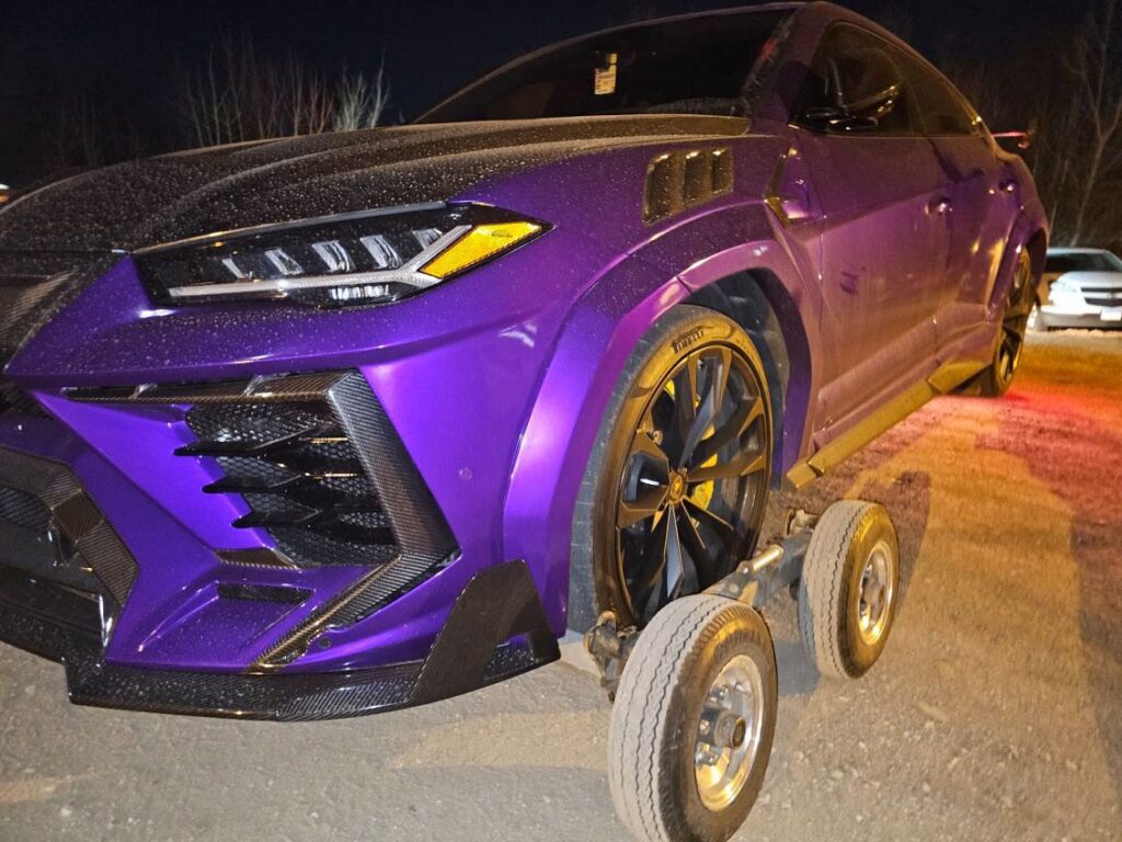 A purple Lamborghini Urus being prepared for towing with dollies by TowTime Towing and Recovery in Bloomington, IN.