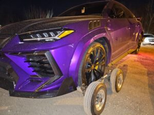 A purple Lamborghini Urus being prepared for towing with dollies by TowTime Towing and Recovery in Bloomington, IN.