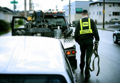 A towing operator walking towards a vehicle with a tow truck in the background for AE Recovery and Towing in Phoenix, AZ.