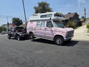 Orellanas Towing & Junk Car tow truck actively towing a pink camper van in Los Angeles, CA.