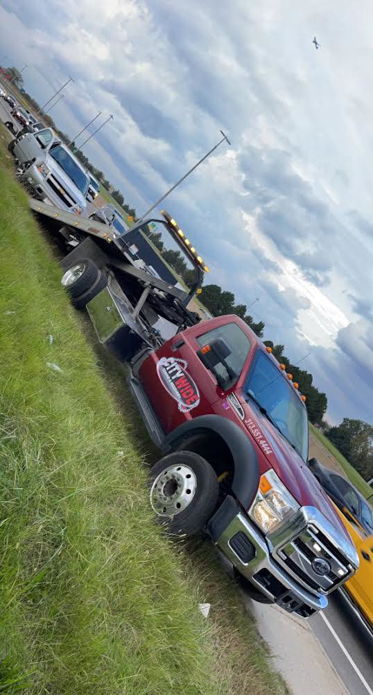 A Citywide Towing Services flatbed truck towing a silver SUV on the side of a road in Dearborn, MI.