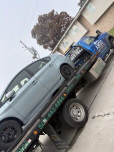 A light blue Toyota Prius being transported on a flatbed tow truck by ABOD Towing LLC in New Orleans, LA.