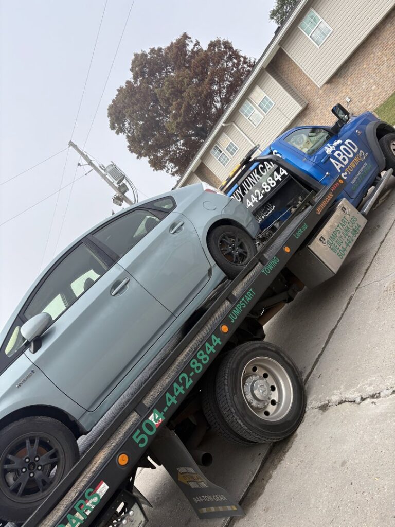 A light blue Toyota Prius being transported on a flatbed tow truck by ABOD Towing LLC in New Orleans, LA.
