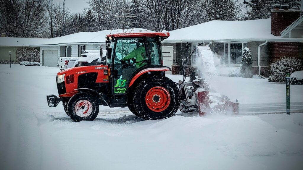 A JD Lawn Care LLC tractor with a snow blower clearing a residential driveway in Berea, OH.
