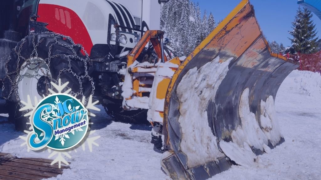 A tractor equipped with a large snow plow blade, ready for or actively engaged in snow removal by JC Snow Management in Mount Vernon, NY