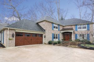 A traditional brick house featuring a brown garage door with windows installed by Pioneer Overhead Door, Inc in Las Vegas, NV.