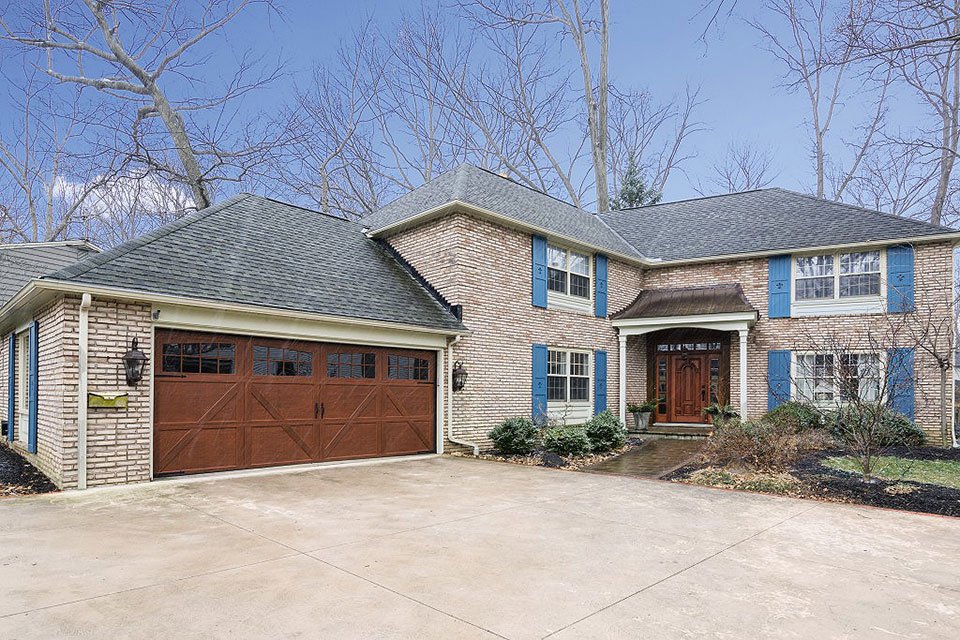 A traditional brick house featuring a brown garage door with windows installed by Pioneer Overhead Door, Inc in Las Vegas, NV.