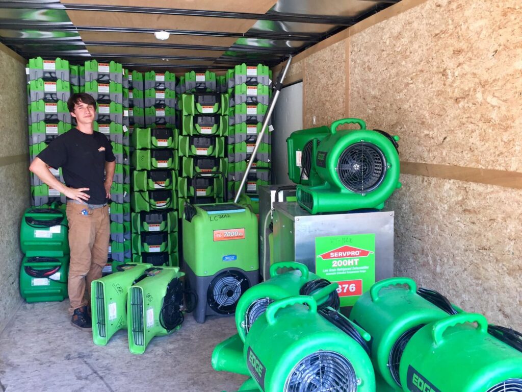 A SERVPRO technician standing in a trailer packed with numerous air movers and dehumidifiers, ready for water damage restoration jobs in Alexandria, LA.