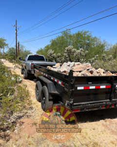 A truck hauling a dump trailer filled with demolition debris on a job site for Solid Scoops Construction in Tucson, AZ.