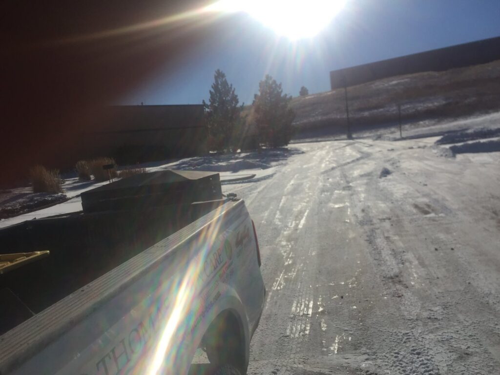A TLC Lawn Care and Snow Removal LLC truck on a snowy road after plowing in Colorado Springs, CO.