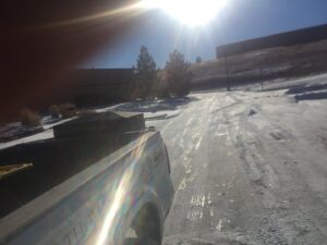 A TLC Lawn Care and Snow Removal LLC truck on a snowy road after plowing in Colorado Springs, CO.
