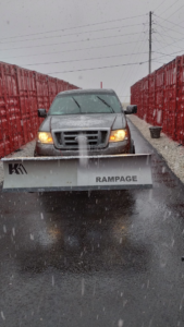 A truck equipped with a snow plow actively removing snow during a snowfall by Kickin Grass Lawncare LLC in Springdale, AR.