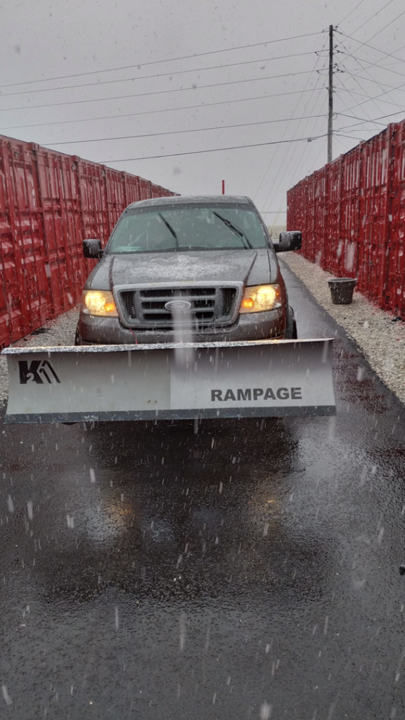 A truck equipped with a snow plow actively removing snow during a snowfall by Kickin Grass Lawncare LLC in Springdale, AR.