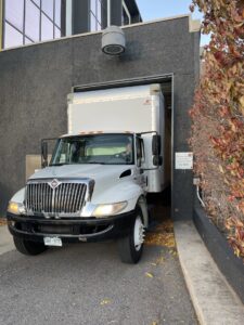 A TruMoving truck carefully backing into a loading dock at a commercial building in Lakewood, CO.