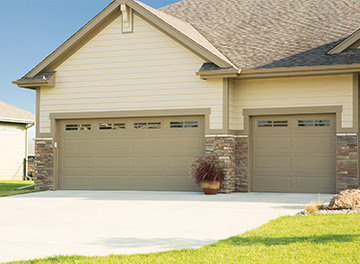 Two beige garage doors with top windows on a residential home, installed by K & B Door Co. in Las Vegas, NV