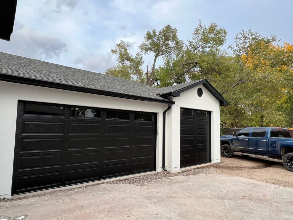 Two black panel garage doors with windows installed on a residential property by Excellence Garage DOORS LLC in Los Angeles, CA