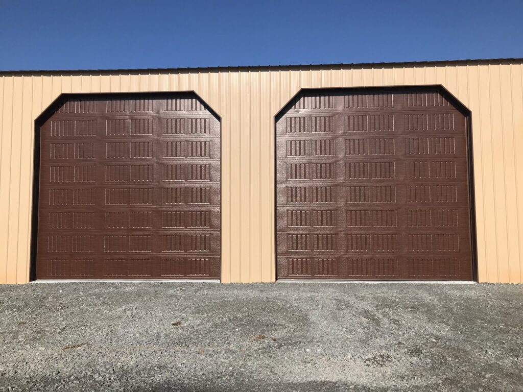 Two brown commercial-style garage doors installed on a tan metal building by LaFrancis Overhead Door LLC in Little Rock, AR