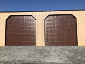 Two brown commercial-style garage doors installed on a tan metal building by LaFrancis Overhead Door LLC in Little Rock, AR
