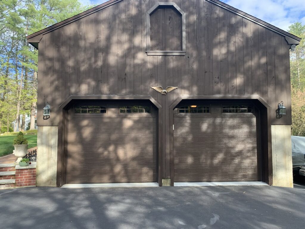 Two brown garage doors with arched windows and decorative hardware installed by J.A. Overhead Door in Westfield, MA.
