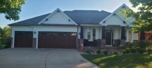 Two brown garage doors with decorative windows installed on a yellow house by ABC Garage Doors KC in Kansas City, KS.