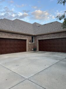 Two brown panel garage doors installed on a brick home by ABC Garage Doors KC in Kansas City, KS.