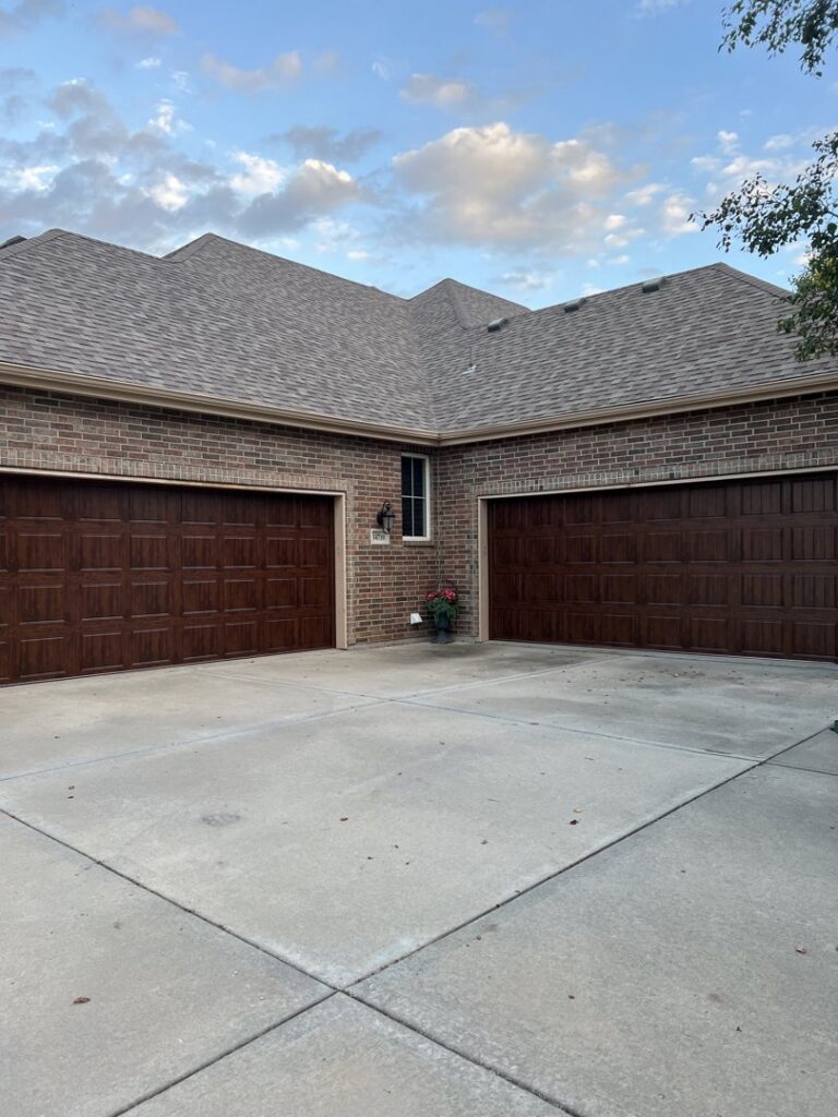 Two brown panel garage doors installed on a brick home by ABC Garage Doors KC in Kansas City, KS.