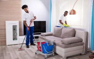 Two house cleaners from Denver MOP STARS Cleaning Service mopping and wiping a living room in Denver, CO.