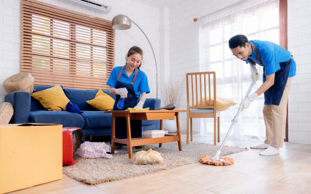 Two professional cleaners from Harsh's Cleaning Services LLC mopping and wiping a living room in Canton, OH.