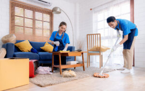 Two professional cleaners from Harsh's Cleaning Services LLC mopping and wiping a living room in Canton, OH.