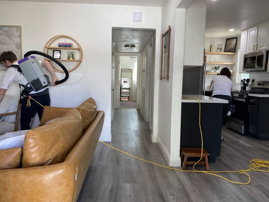 Two professional cleaners from Mr. & Mrs. K Cleaning Services LLC vacuuming and cleaning a kitchen in Sacramento, CA.