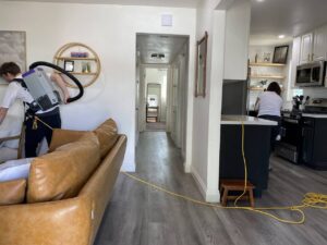 Two professional cleaners from Mr. & Mrs. K Cleaning Services LLC vacuuming and cleaning a kitchen in Sacramento, CA.