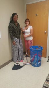 Two professional cleaners holding a broom and mop, ready for work with Divine Cleaning in Fargo, ND.