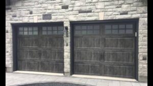 Two dark grey wood-grain style garage doors with windows installed by Elite Garage Door Service & Repair in Billings, MT.