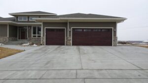 Two dark wood-look garage doors installed on a modern home by Cedar Valley Garage Doors in Waterloo, IA