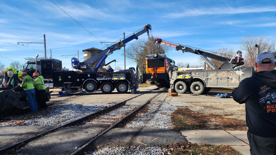 Two heavy-duty tow trucks from Elmquist Towing & Recovery working to recover a train locomotive in Ames, IA.