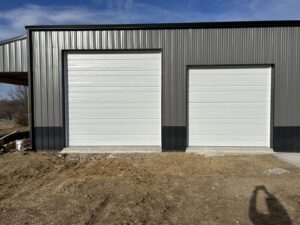 Two white industrial-style garage doors installed on a metal building by Woodwards Overhead Door Co. in Topeka, KS