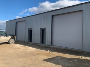 Two large grey industrial-style garage doors installed on a metal building by Devildog Dock N Door in Helena, MT.