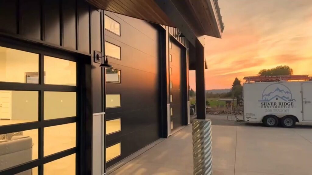 Two modern black garage doors with windows installed on a commercial or large residential building, a project by North Idaho Garage Door in Coeur d'Alene, ID.
