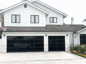 A white residential house featuring two modern black glass garage doors installed by NV Pro Garage Doors in Las Vegas, NV.