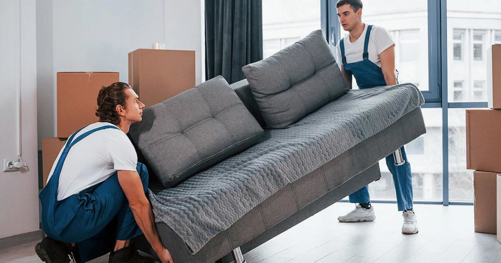 Two professional movers from 4D Extreme Movers carrying a sofa into a home in Atlanta, GA.