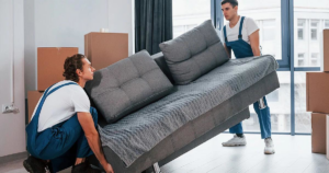 Two professional movers from 4D Extreme Movers carrying a sofa into a home in Atlanta, GA.