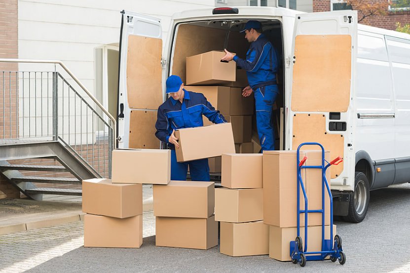 Two professional movers loading cardboard boxes into a white moving van with a dolly nearby for Las Vegas Moving Pros LLC in Las Vegas, NV.