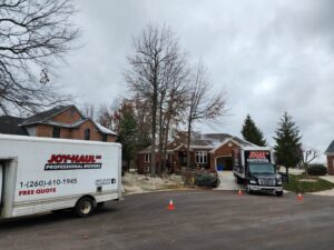 Two Joy Haul Professional Movers trucks parked outside a house, prepared for a moving service in Columbia City, IN.